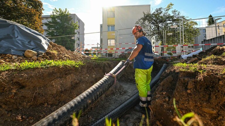 Brugg Pipes - Bild eines Arbeiters, der Fernwärmeleitung verlegt.